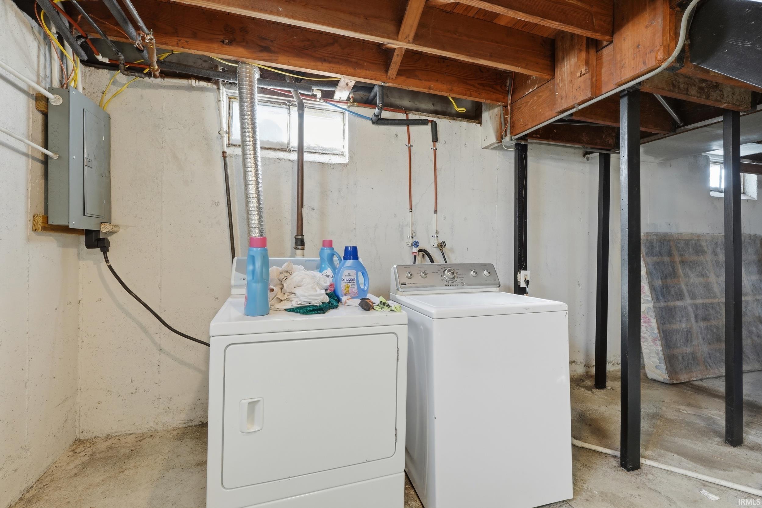 Laundry area with concrete floors, electric panel, and separate washer and dryer