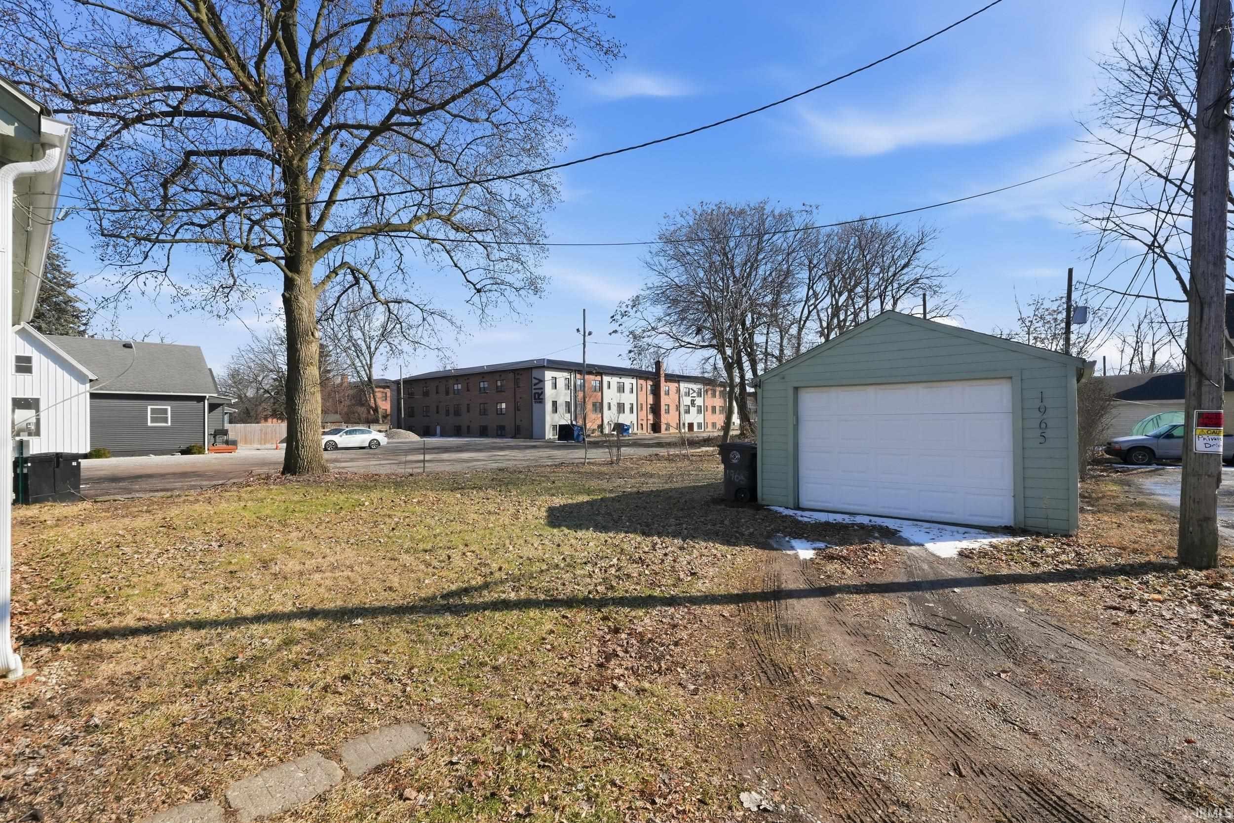 View of yard with a detached garage, an outdoor structure, and dirt driveway