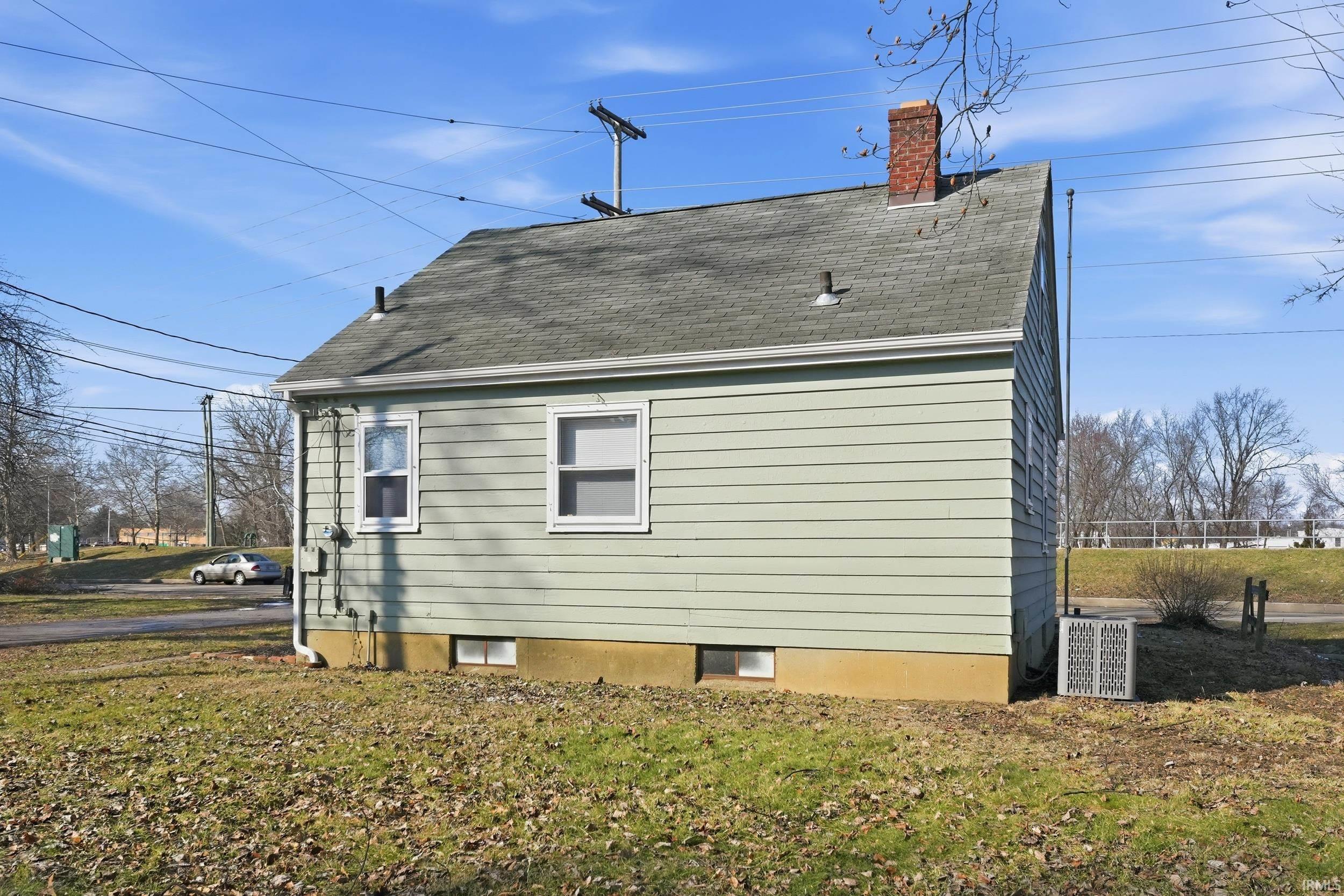 View of home's exterior with a chimney, a yard, and a shingled roof