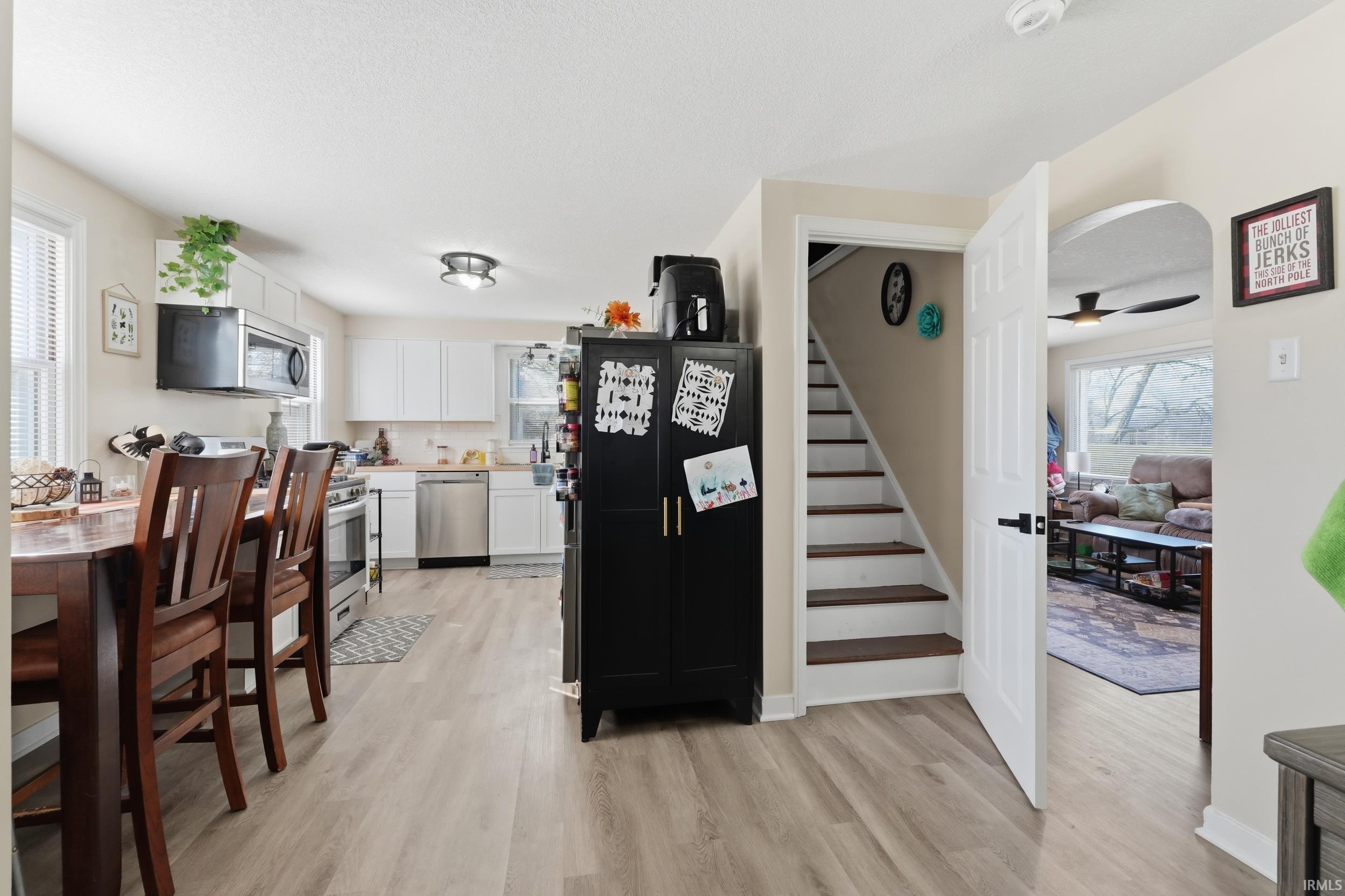 Kitchen featuring stainless steel appliances, light countertops, white cabinetry, and light wood-style flooring
