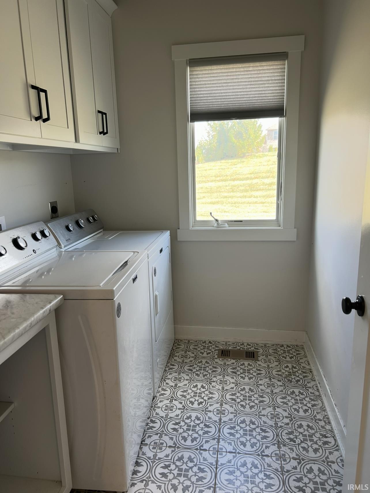 Laundry area featuring washer and clothes dryer, light tile patterned floors, and cabinet space