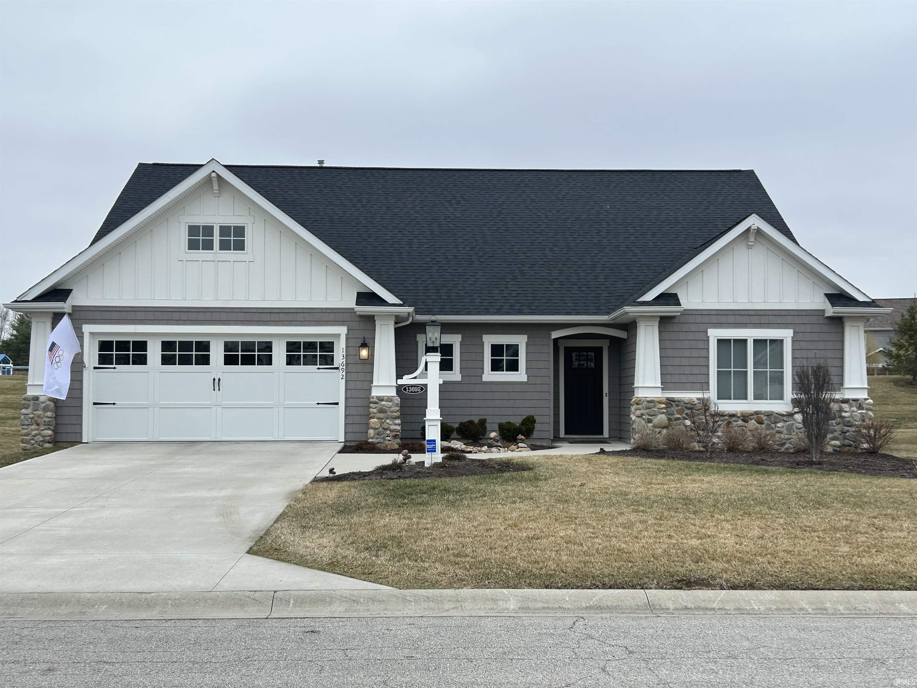 Craftsman-style home featuring a shingled roof, a front lawn, board and batten siding, and stone siding