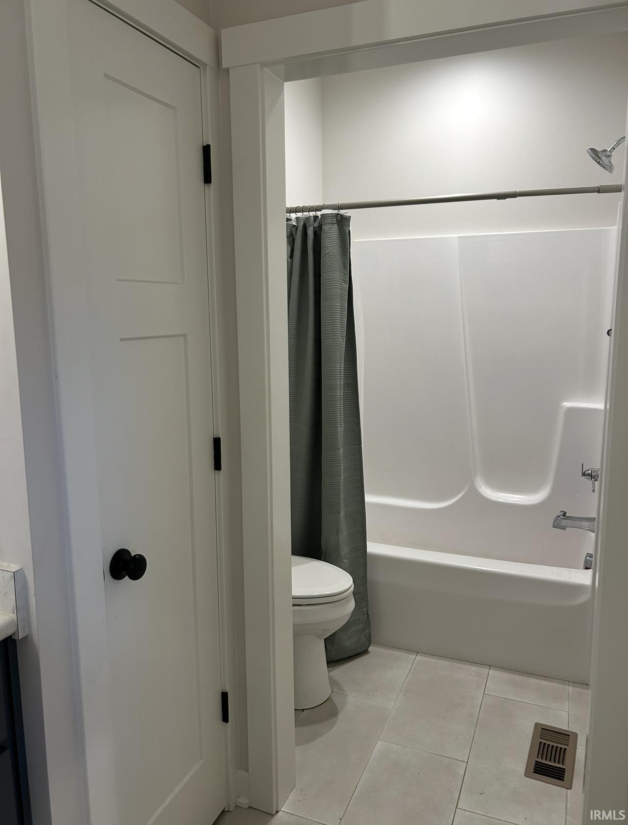Bathroom featuring light tile patterned floors, shower / bath combo with shower curtain, and vanity