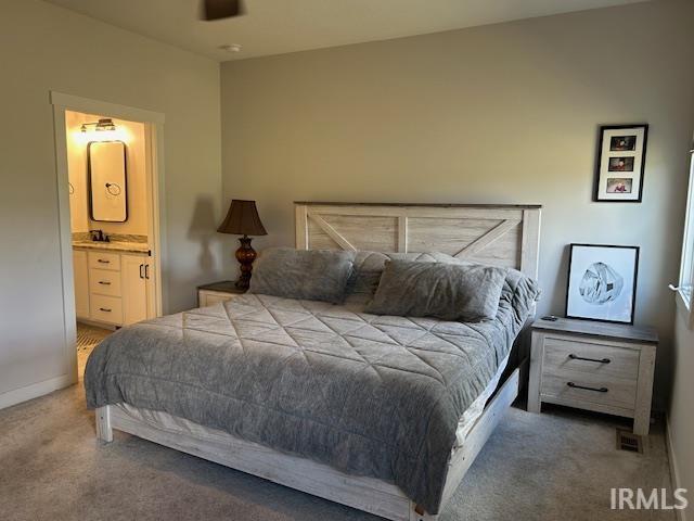 Carpeted bedroom featuring ensuite bath and a ceiling fan