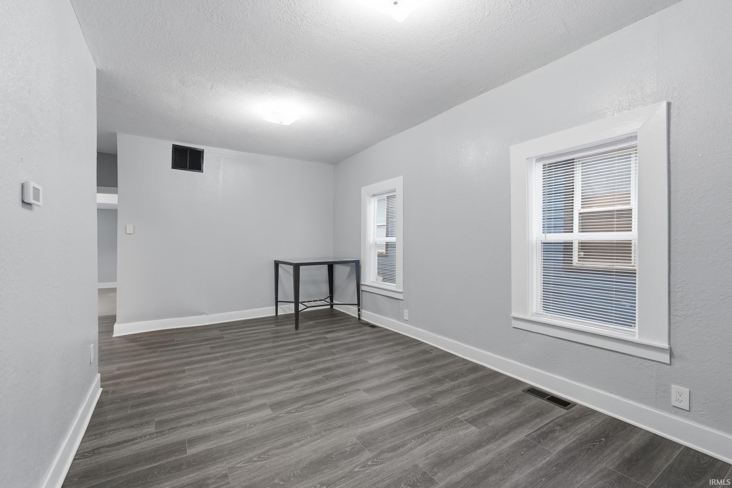 Unfurnished room with dark wood-type flooring and a textured ceiling