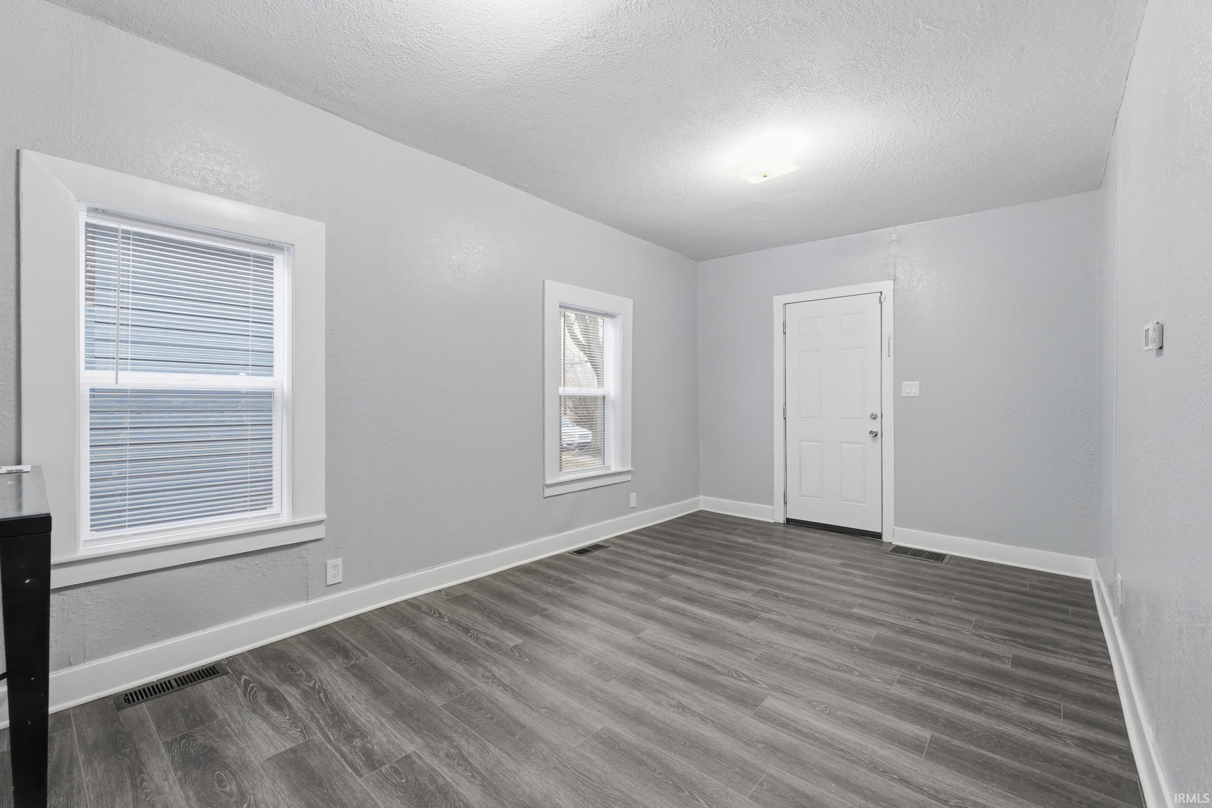 Spare room with dark wood-type flooring and a textured ceiling
