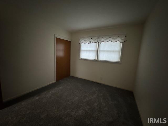Empty room featuring dark carpet