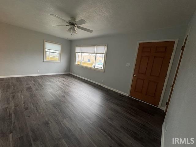 Spare room featuring dark wood-style floors, a textured ceiling, and ceiling fan