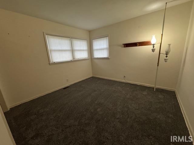 Empty room with dark carpet and baseboards