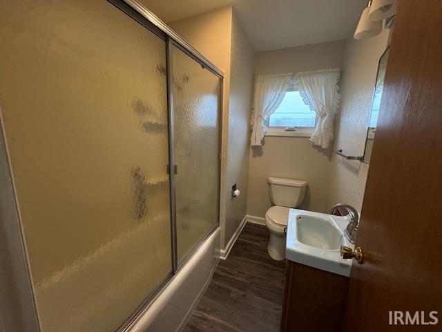 Full bathroom with vanity, dark wood-type flooring, and shower / bath combination with glass door