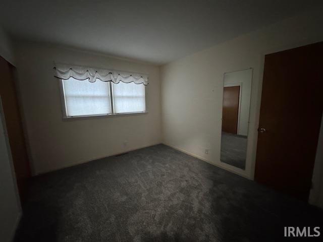 Unfurnished bedroom featuring dark carpet