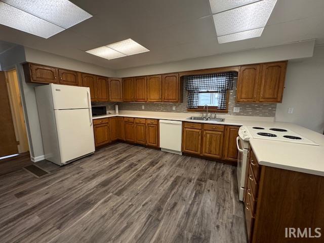 Kitchen with wood finish cabinets, white appliances, light countertops, and a peninsula