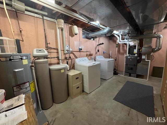 Unfinished below grade area featuring a water softener system, water heater, and washer and dryer