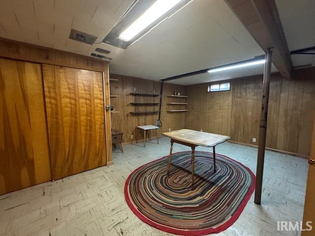 Basement featuring wooden walls and light floors