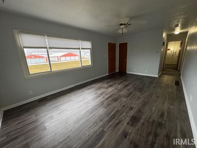 Unfurnished living room with dark wood-style floors and a ceiling fan
