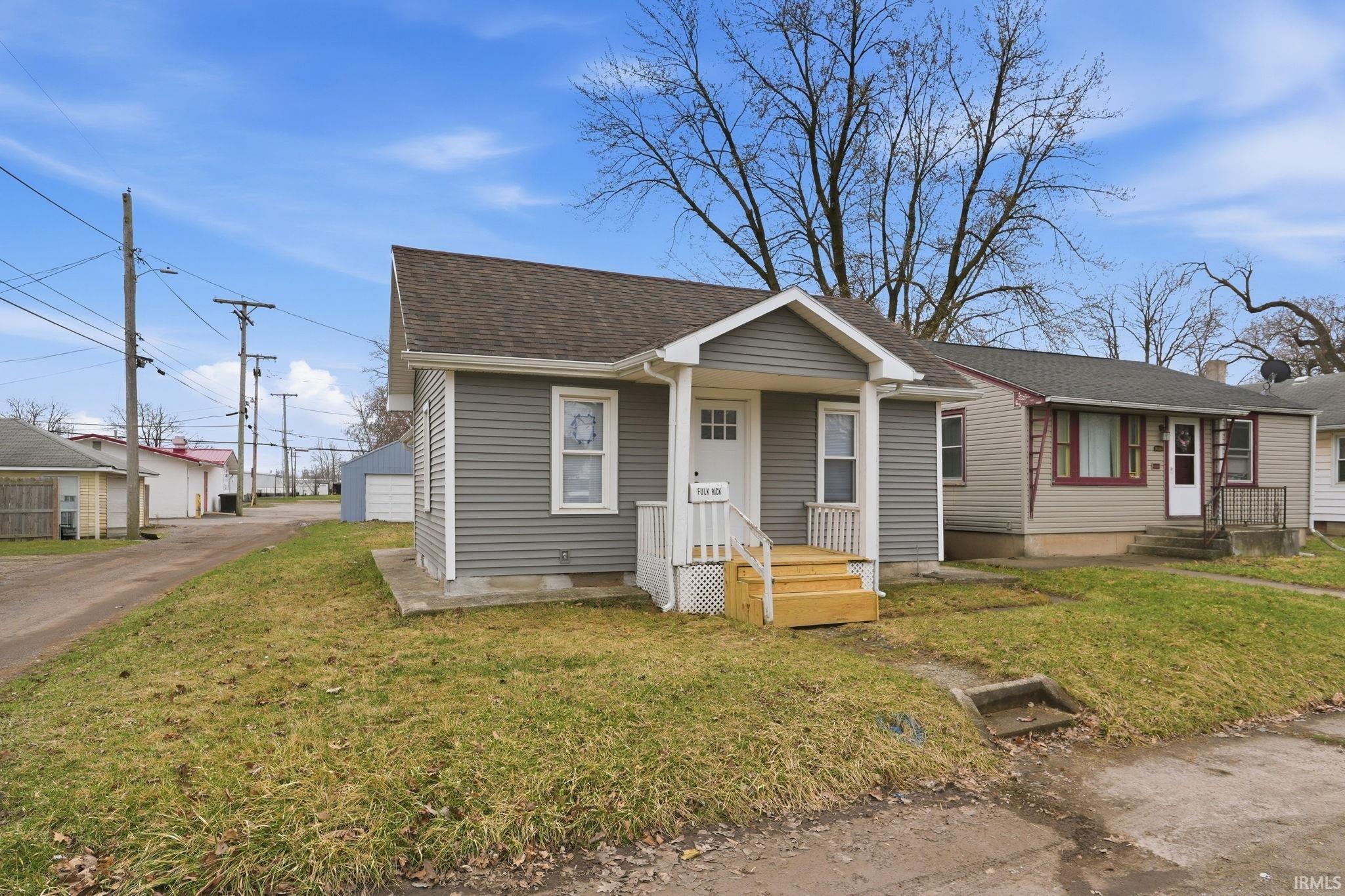 View of front of property with a front lawn, a shingled roof, and an outbuilding