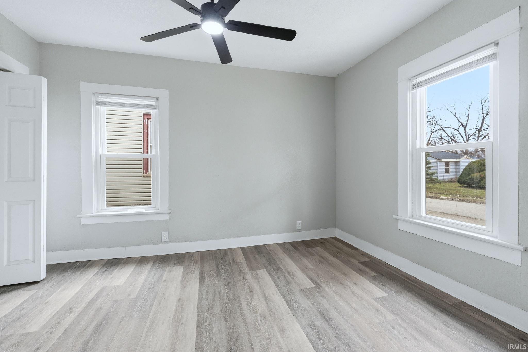 Unfurnished room with light wood finished floors, a ceiling fan, and healthy amount of natural light