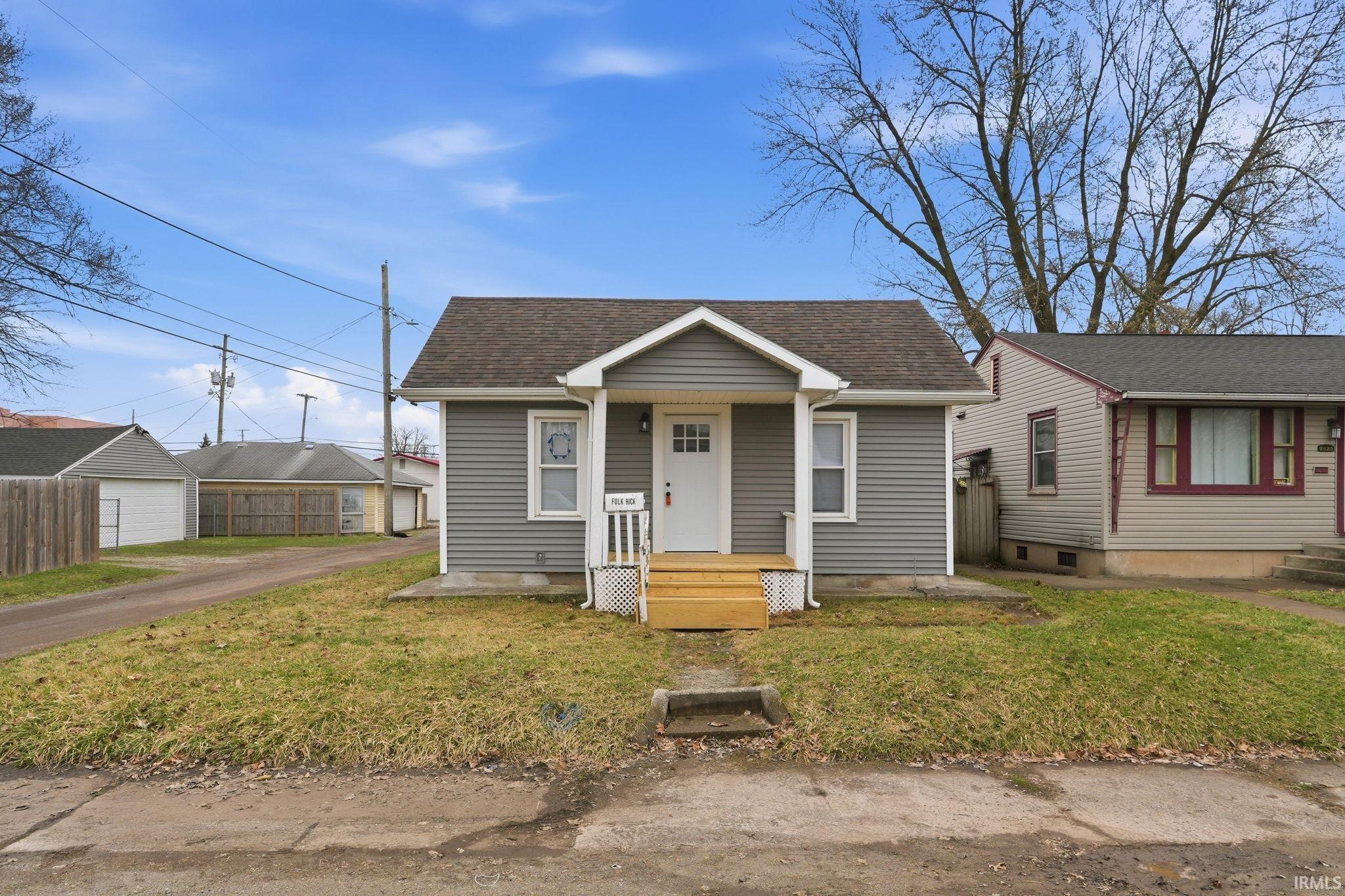 Bungalow-style house featuring covered porch, a shingled roof, and a front yard