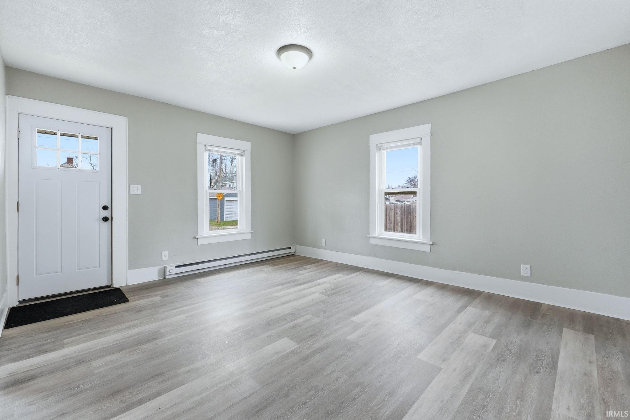 Entrance foyer with a baseboard radiator and light wood-style flooring