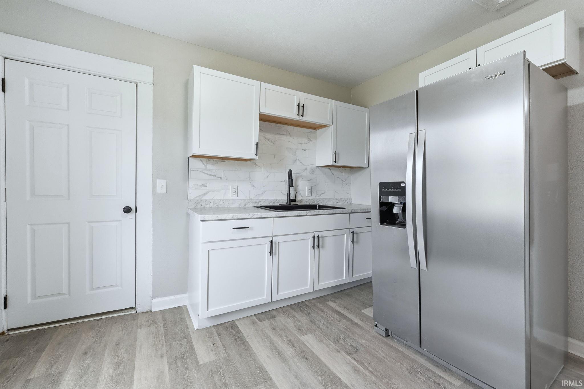 Kitchen featuring stainless steel fridge, light wood-style flooring, and white cabinetry