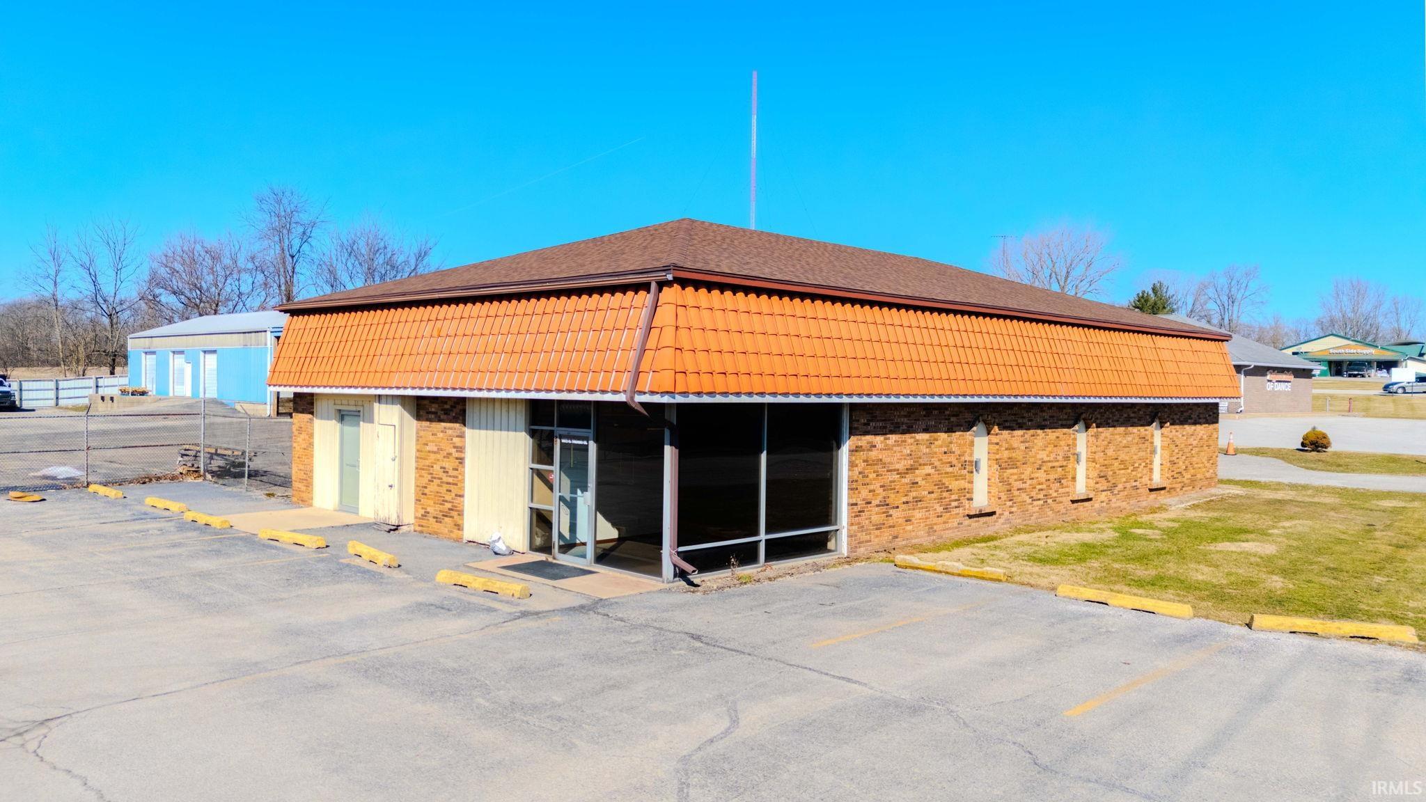 View of side of property featuring brick siding and uncovered parking