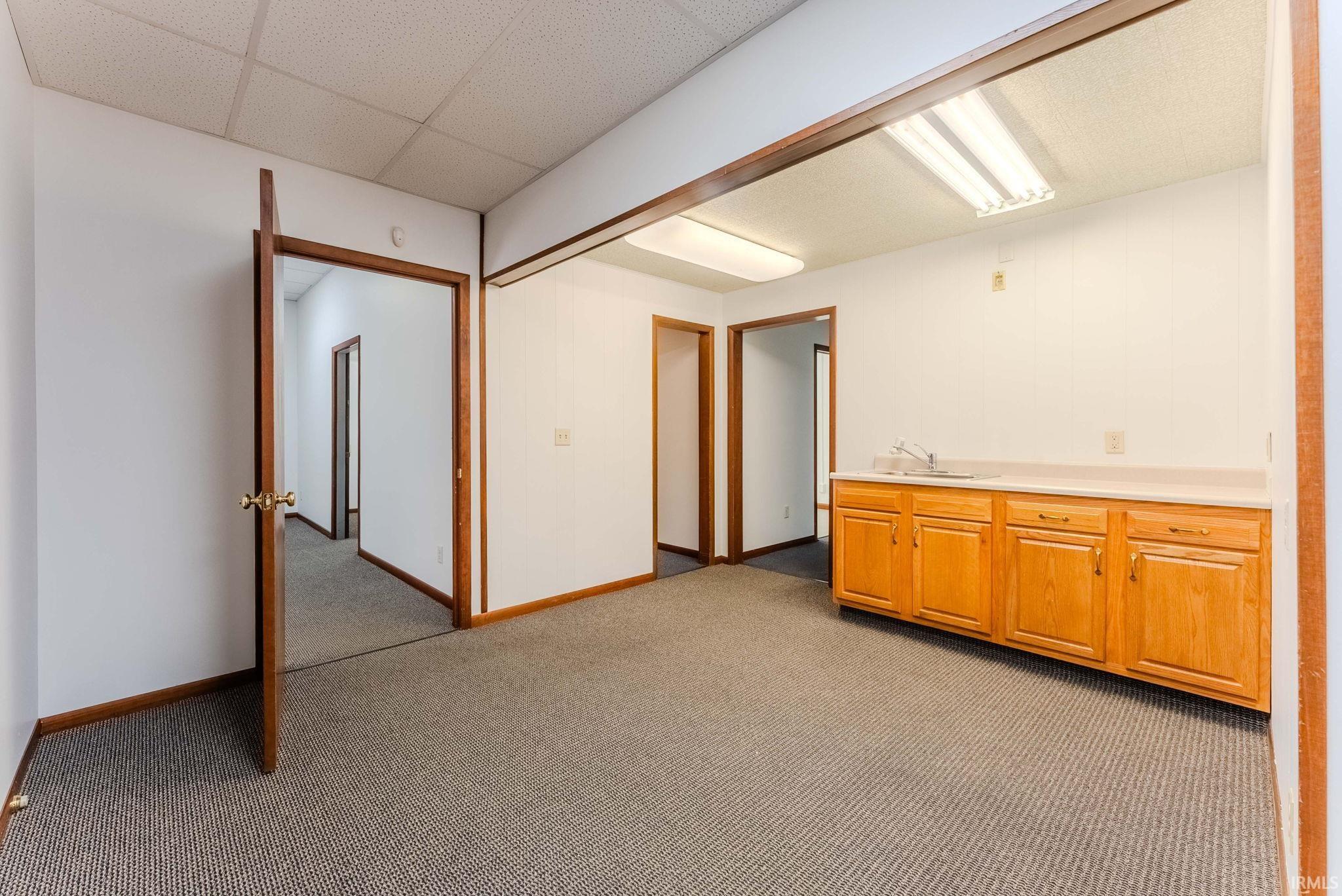 Basement with dark colored carpet and a paneled ceiling