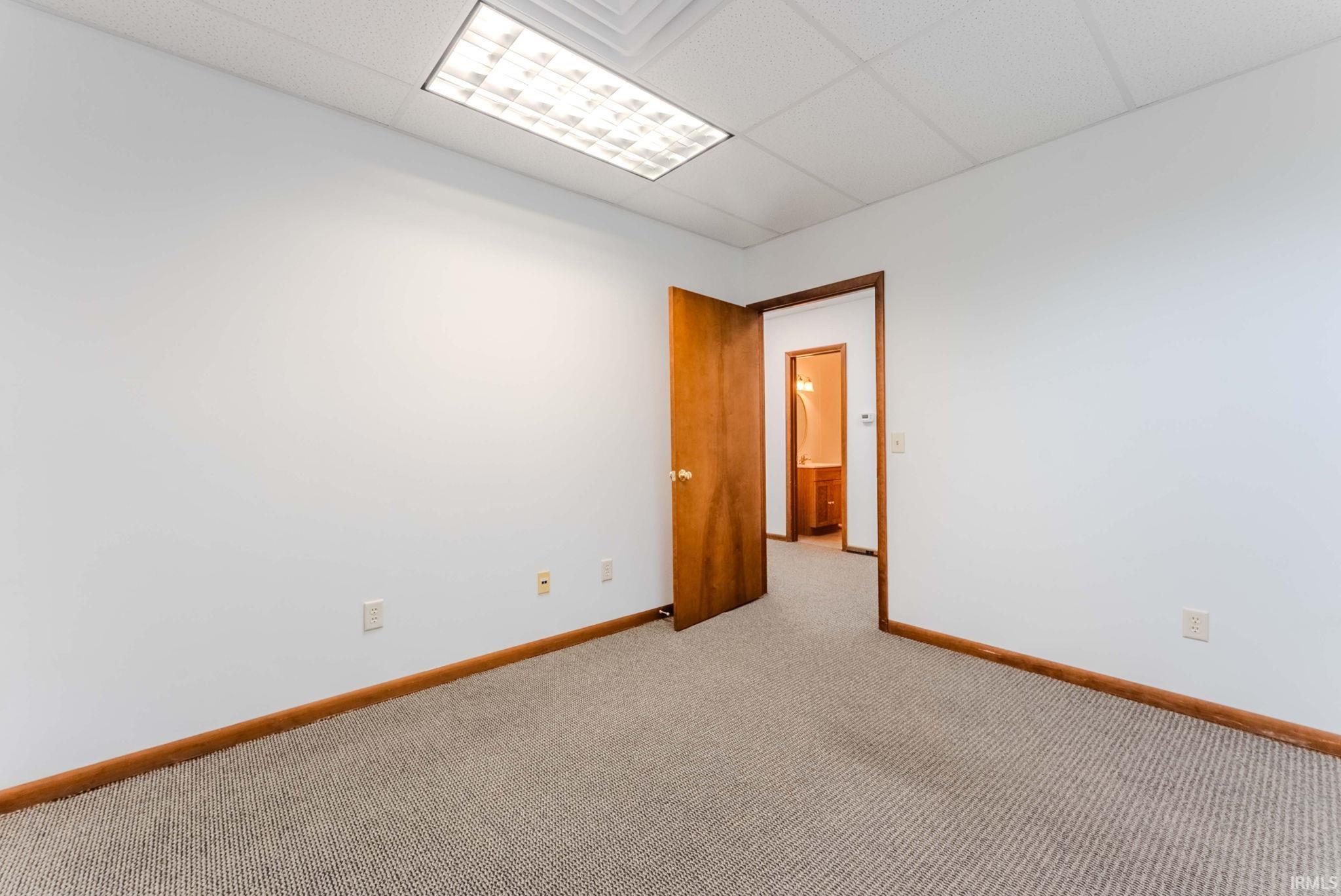Empty room with a paneled ceiling and light colored carpet