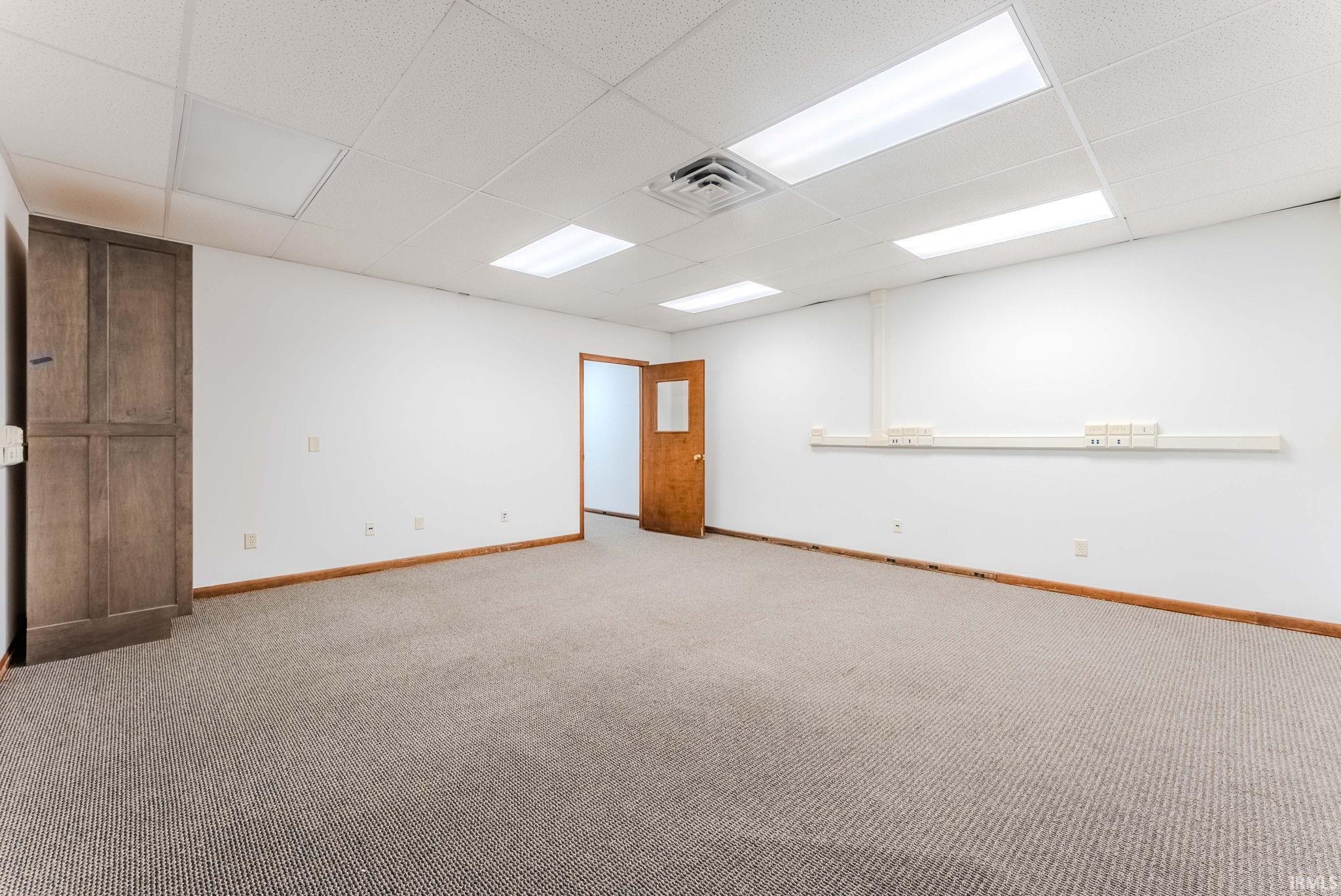 Unfurnished room featuring a drop ceiling and carpet flooring