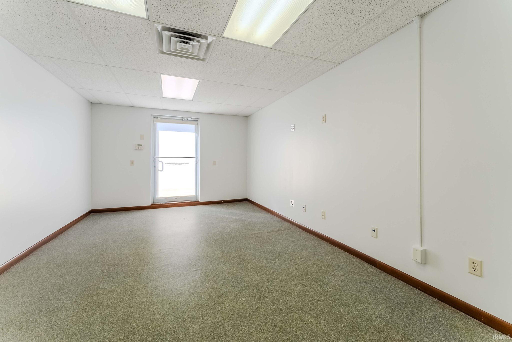 Spare room featuring a paneled ceiling and baseboards