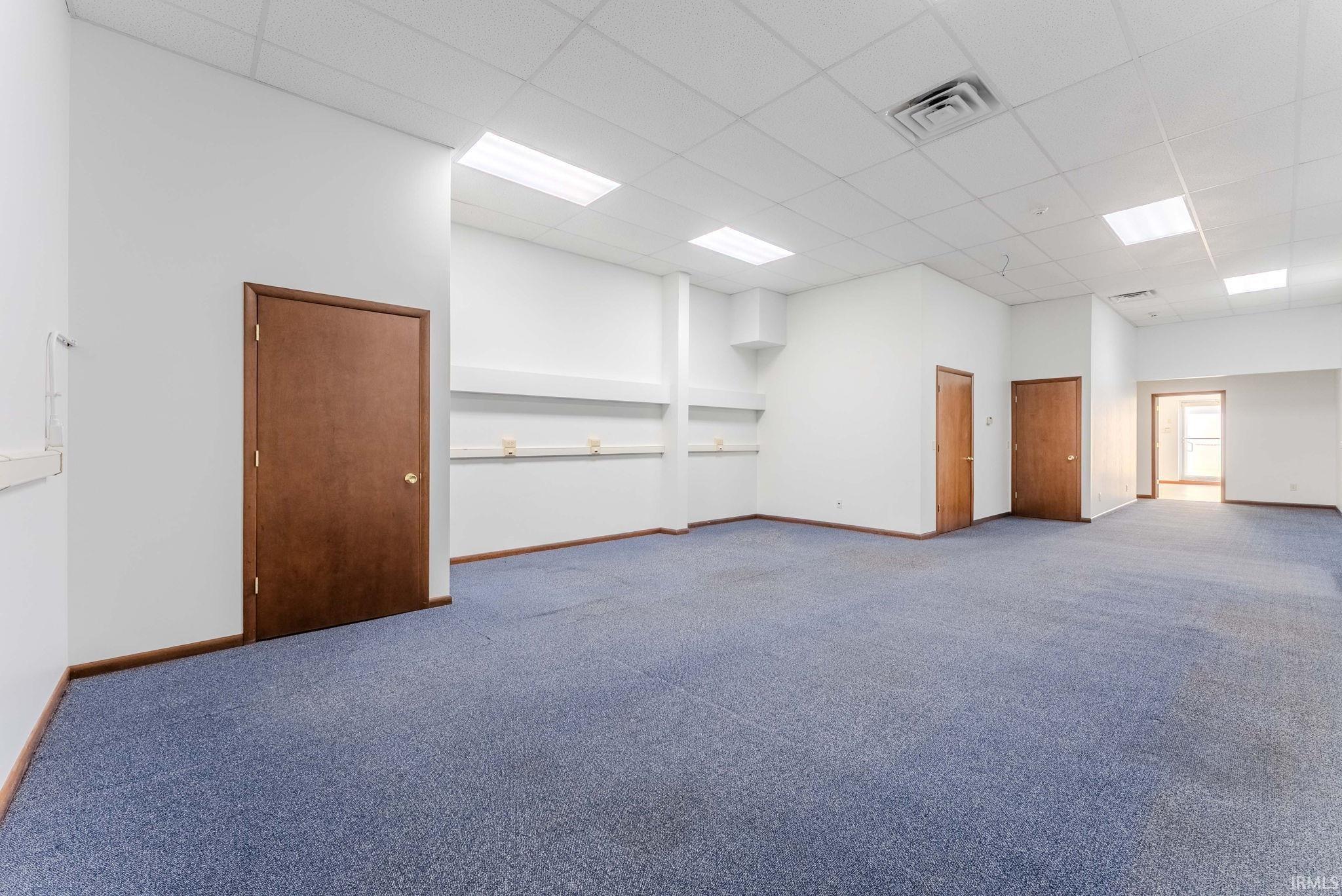 Empty room featuring a paneled ceiling and carpet floors