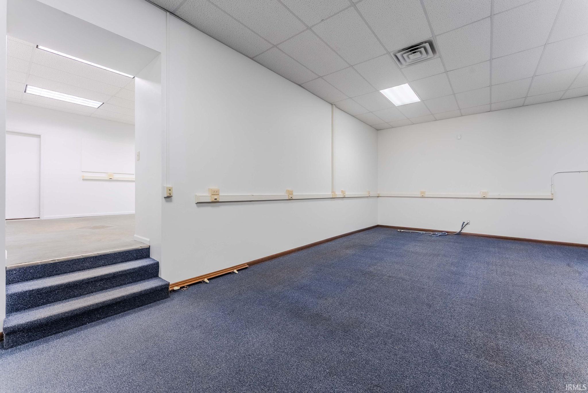 Spare room with a paneled ceiling and carpet flooring