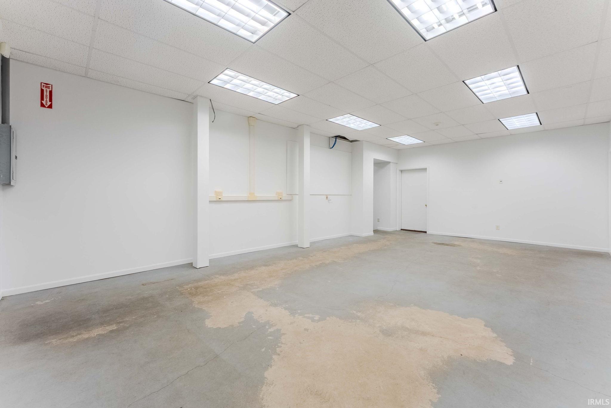 Spare room featuring unfinished concrete flooring and a paneled ceiling