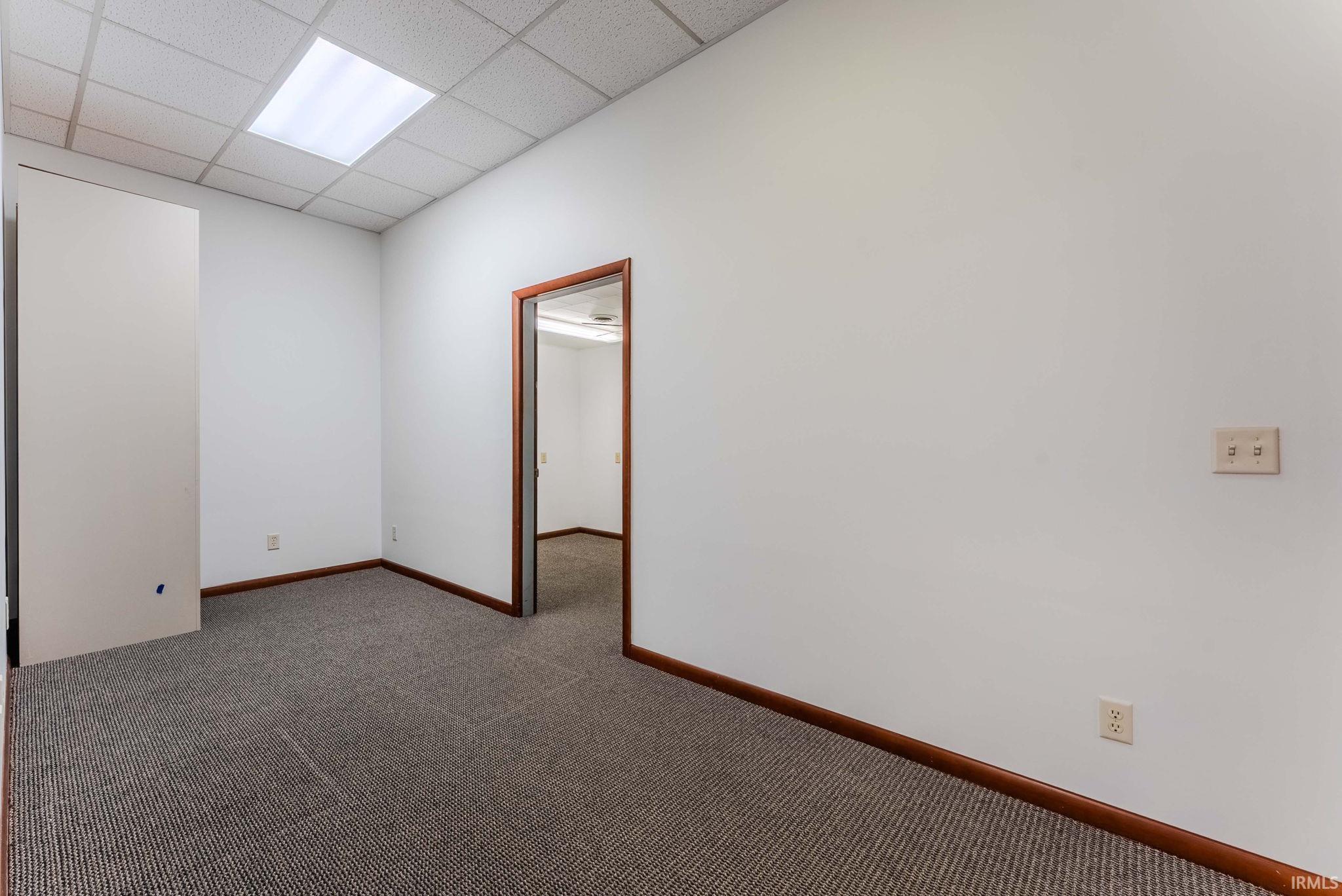 Spare room featuring a drop ceiling and dark carpet