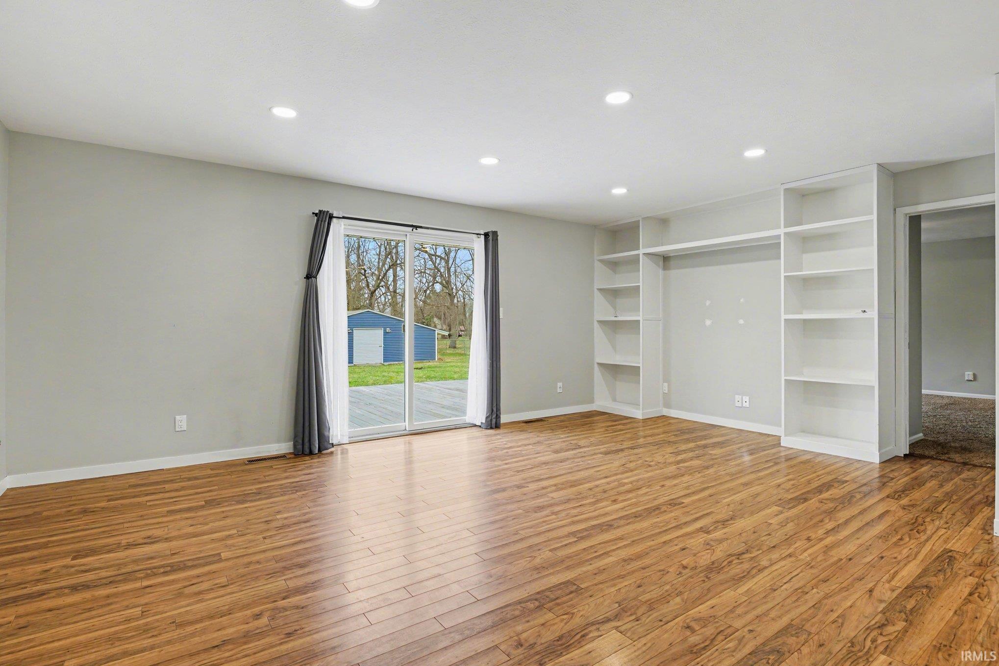 Living room featuring recessed lighting, built-in shelves, and a sliding glass door to the backyard