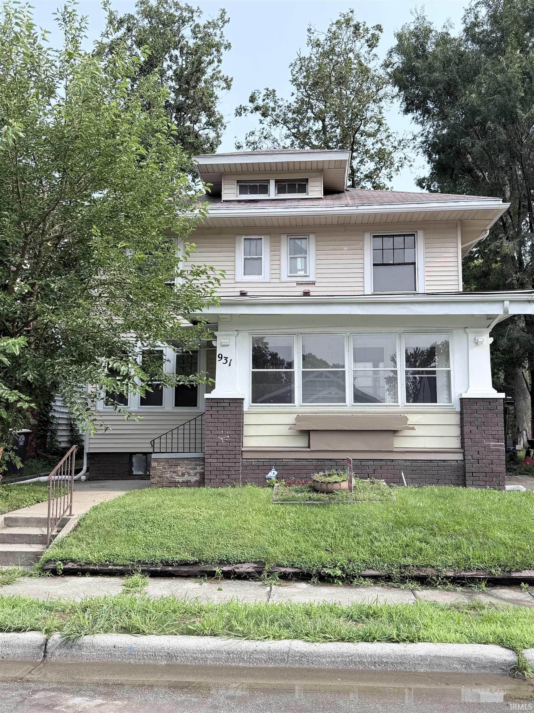 Two-story residence with dormer window, full-light windows, brick detailing, and a front porch
