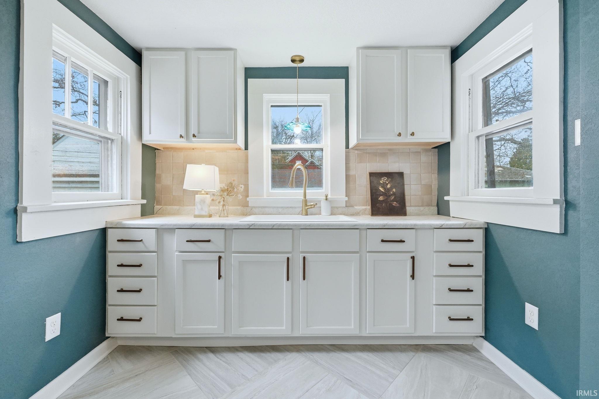 Kitchen featuring white cabinetry, tasteful backsplash, and hanging light fixtures