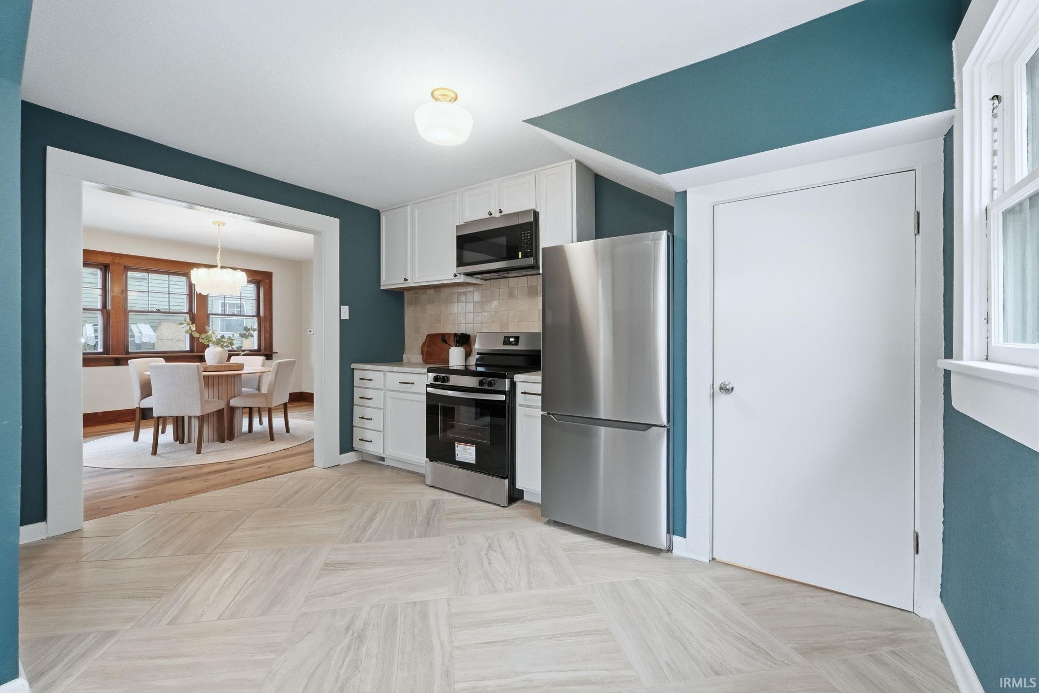 Kitchen with healthy amount of natural light, stainless steel appliances, white cabinets, and light countertops
