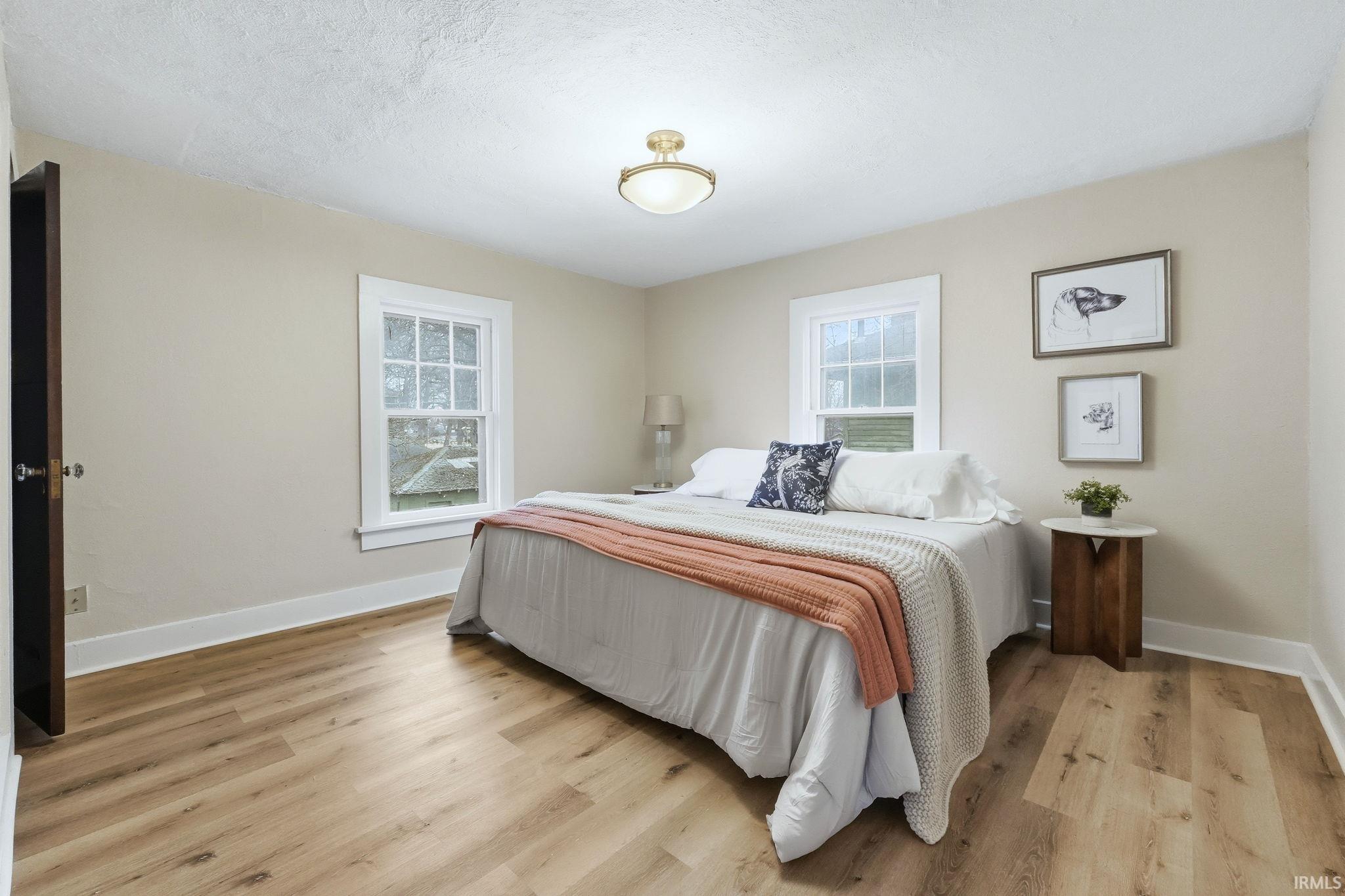 Bedroom with light wood-style floors and a textured ceiling