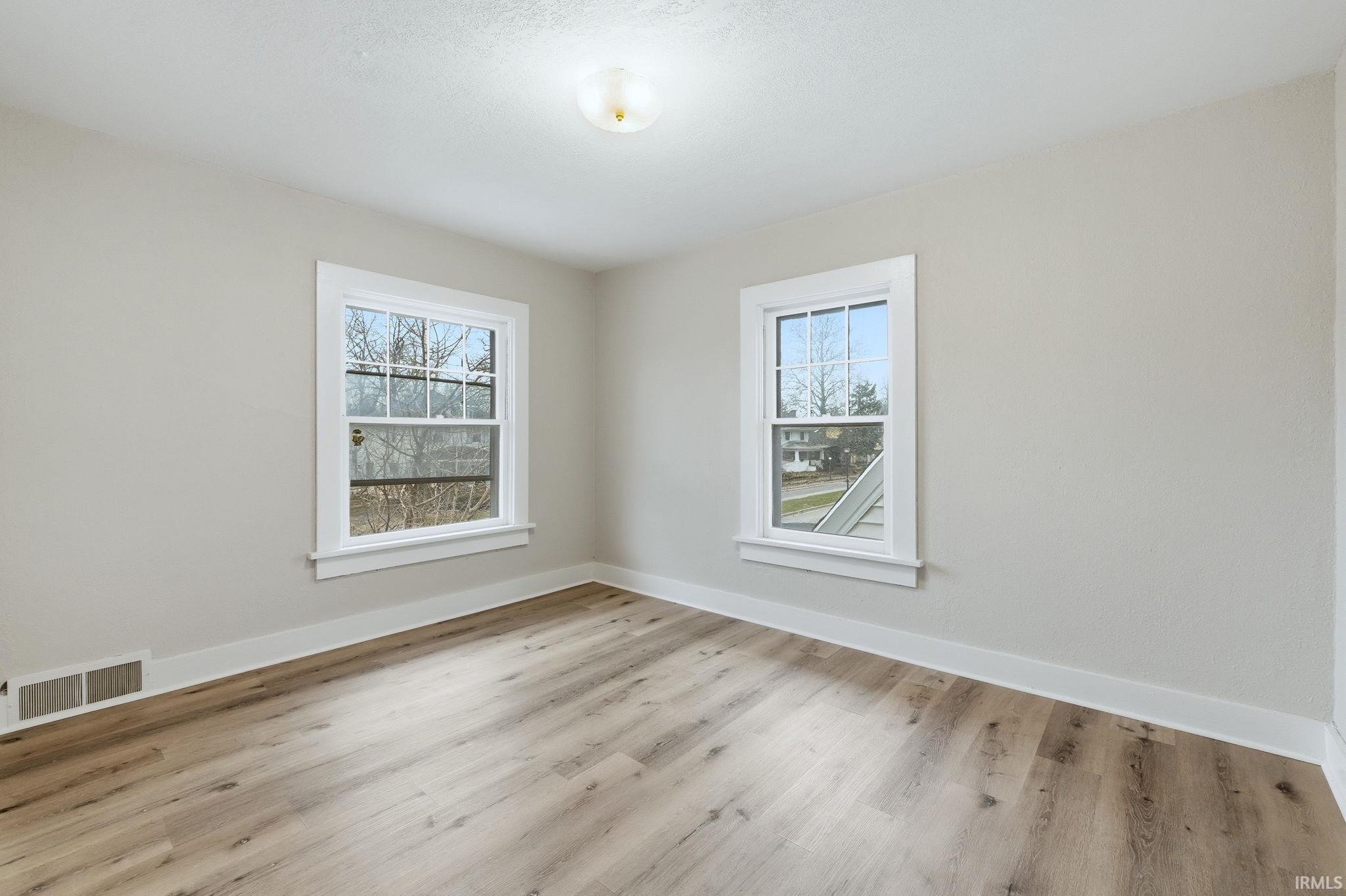 Empty room featuring baseboards and light wood-style flooring