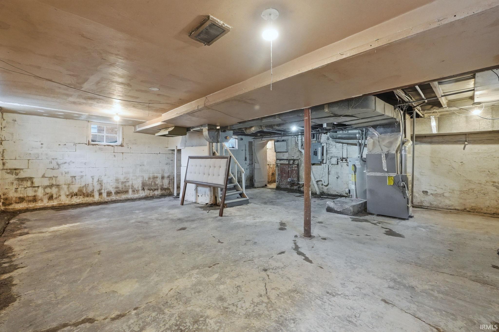 Unfinished basement featuring heating unit and electric panel