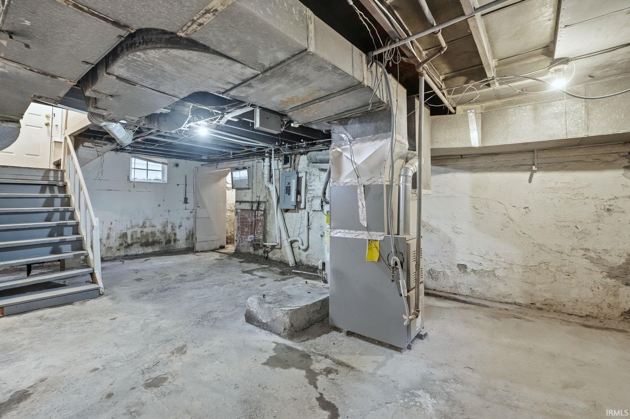 Below grade area featuring heating unit and electric panel