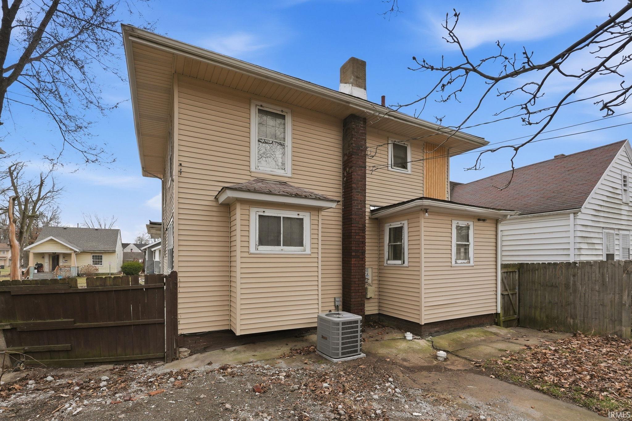 Rear view of house with a fenced backyard and a chimney