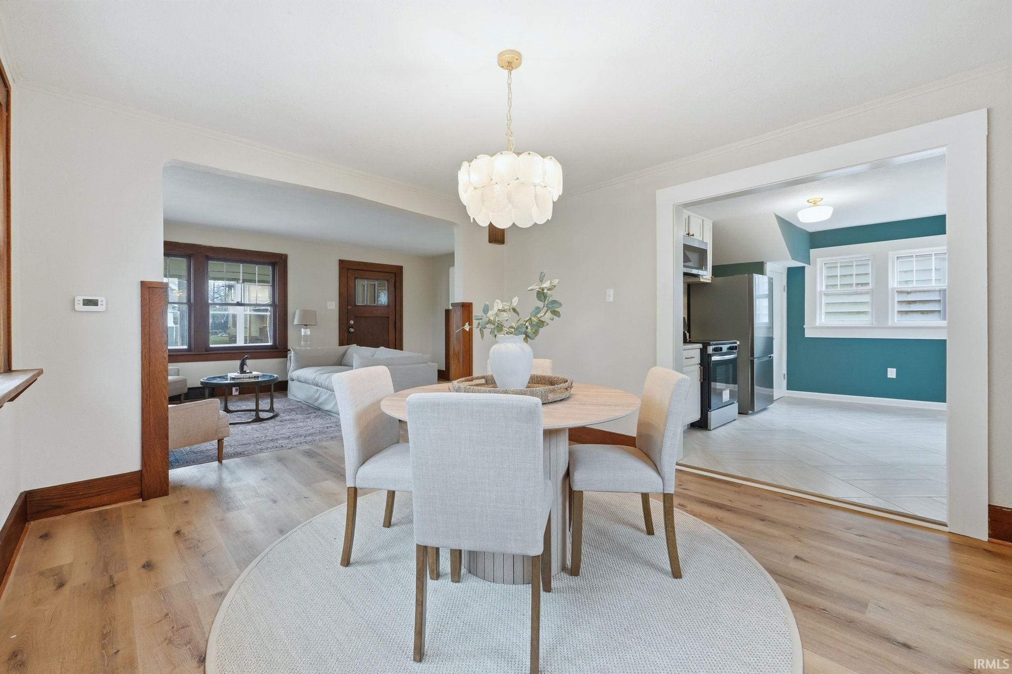 Dining room with light wood-style flooring, suspended lighting, and ornamental molding