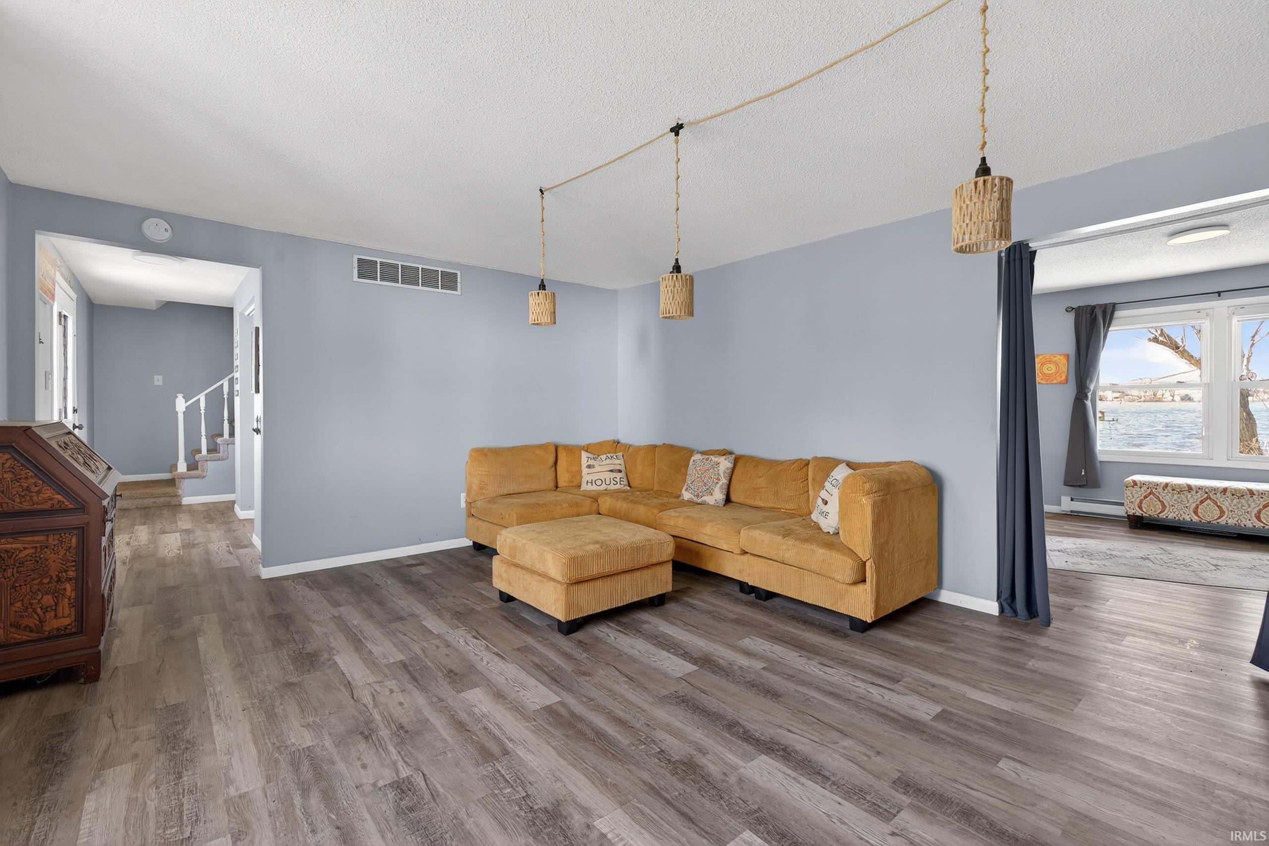 Living area with dark wood-style flooring, a textured ceiling, and a baseboard heating unit