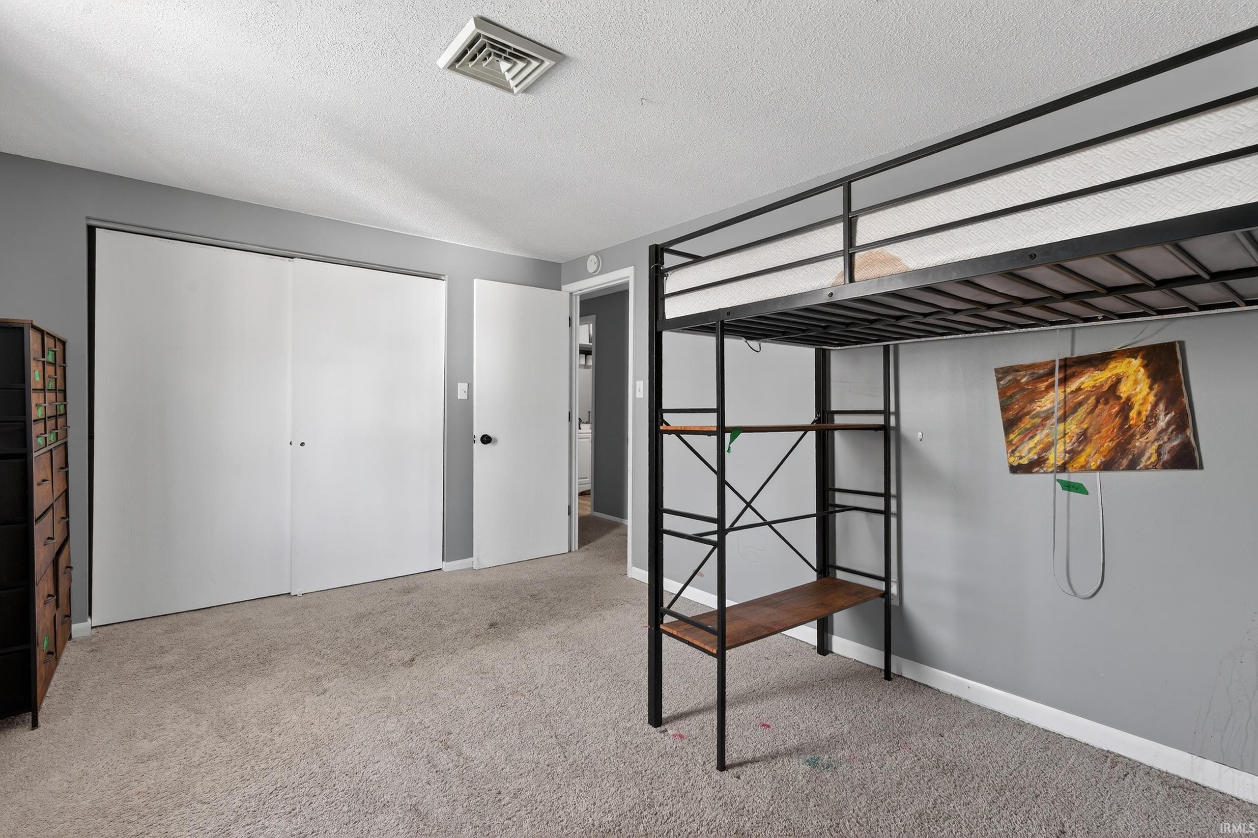 Unfurnished bedroom featuring light carpet, a closet, and a textured ceiling