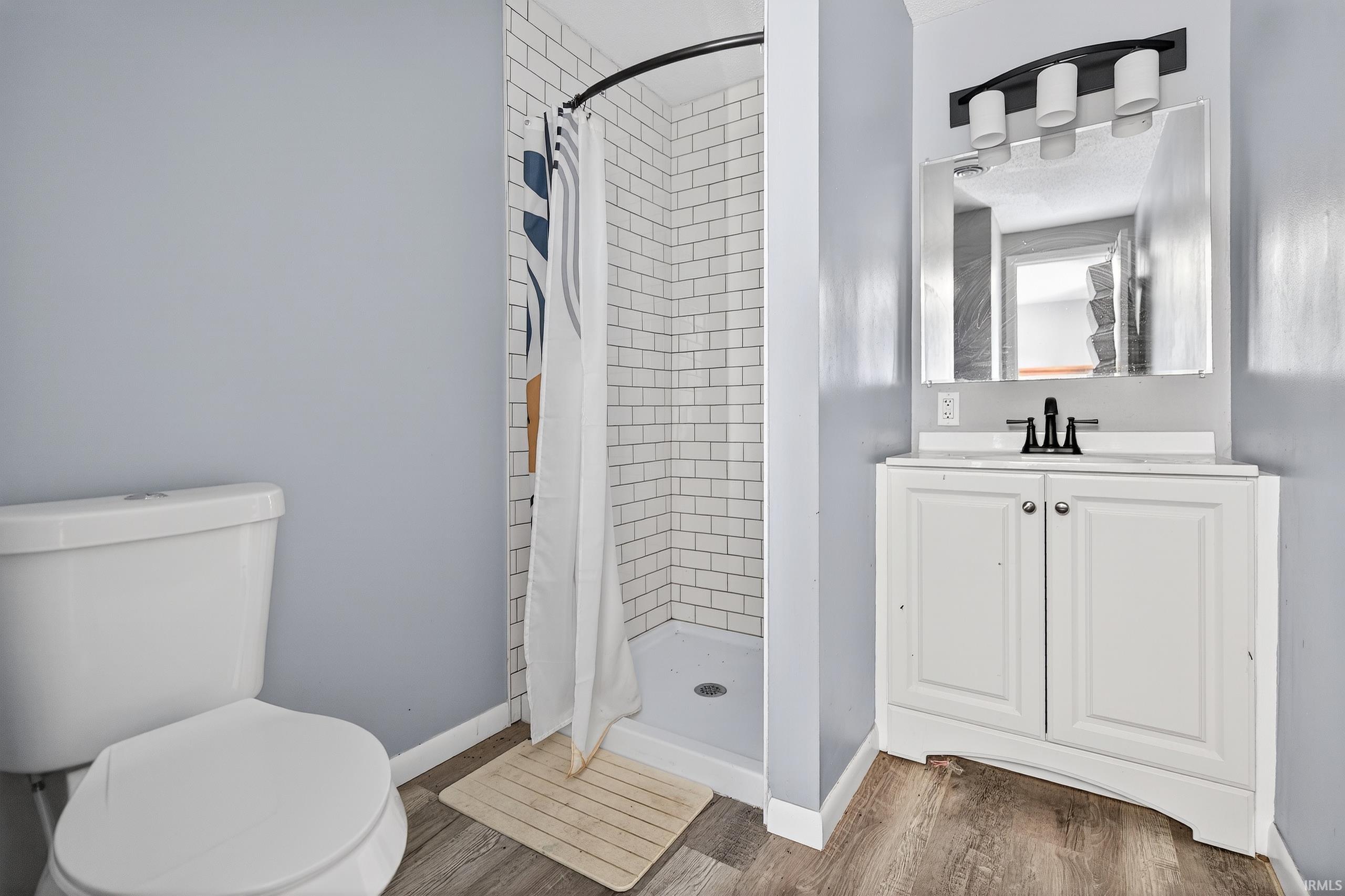 Full bath featuring a stall shower, vanity, and light wood-style floors