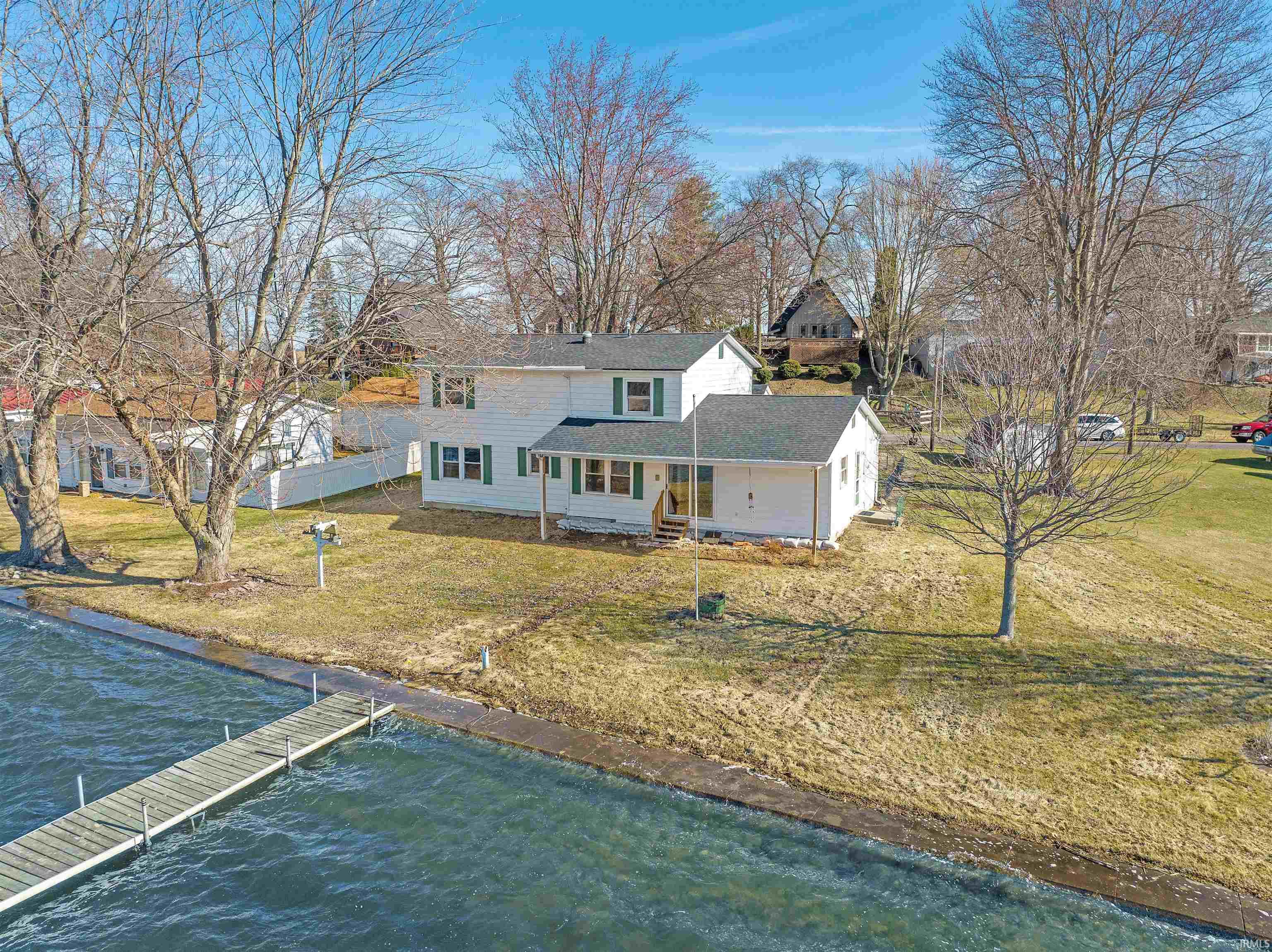 Rear view of house featuring covered porch, a water view, and a yard