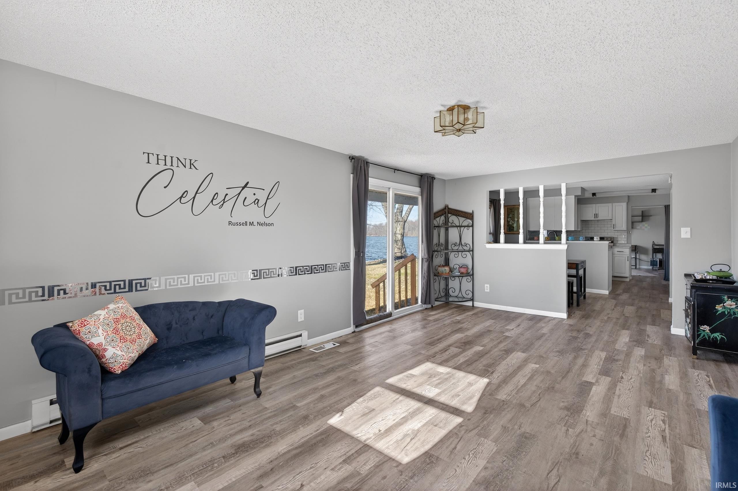 Family room with wood finished floors, a baseboard radiator, a baseboard heating unit, and a textured ceiling