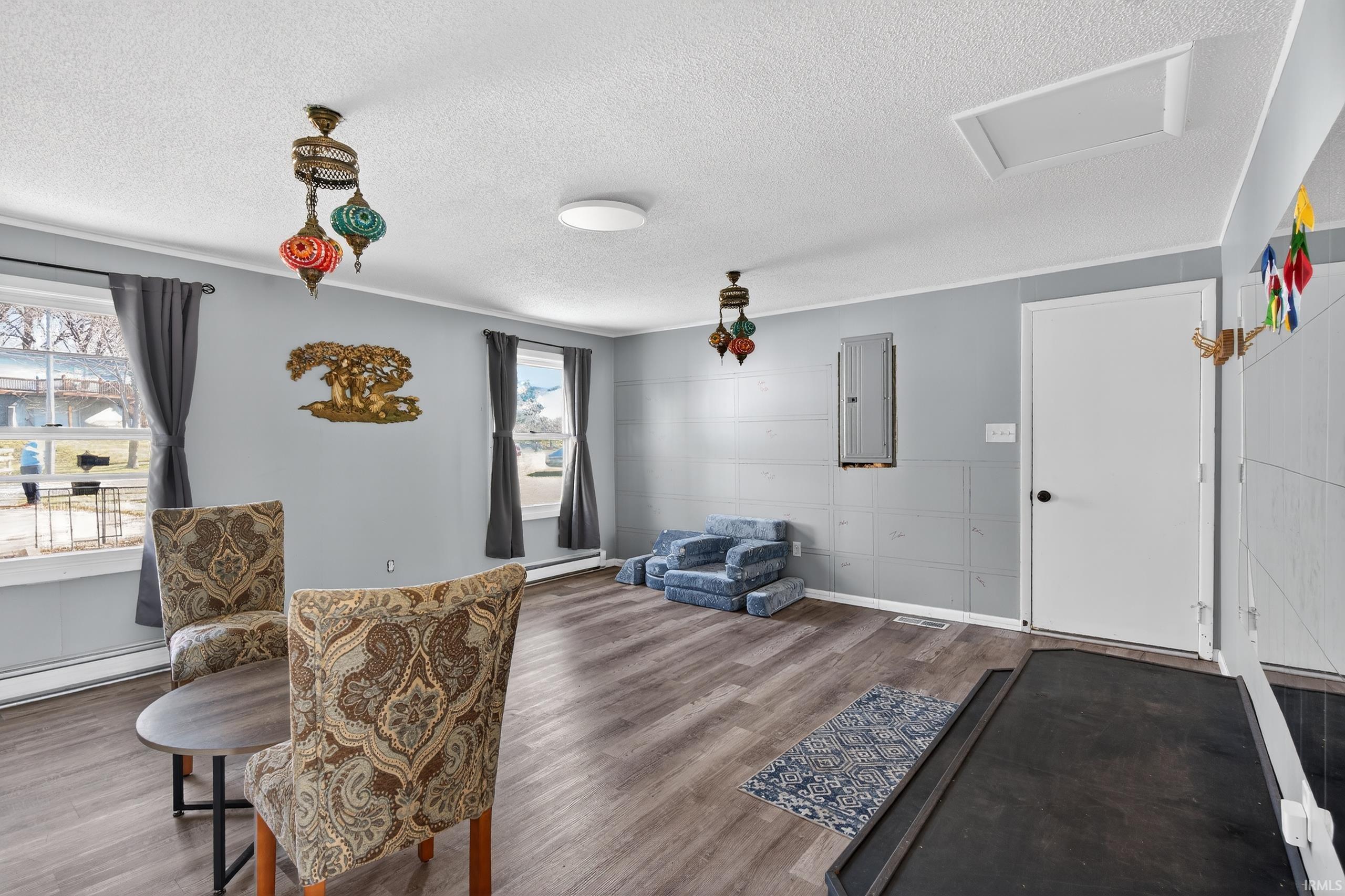 Sitting room featuring wood finished floors, a textured ceiling, electric panel, and a baseboard radiator