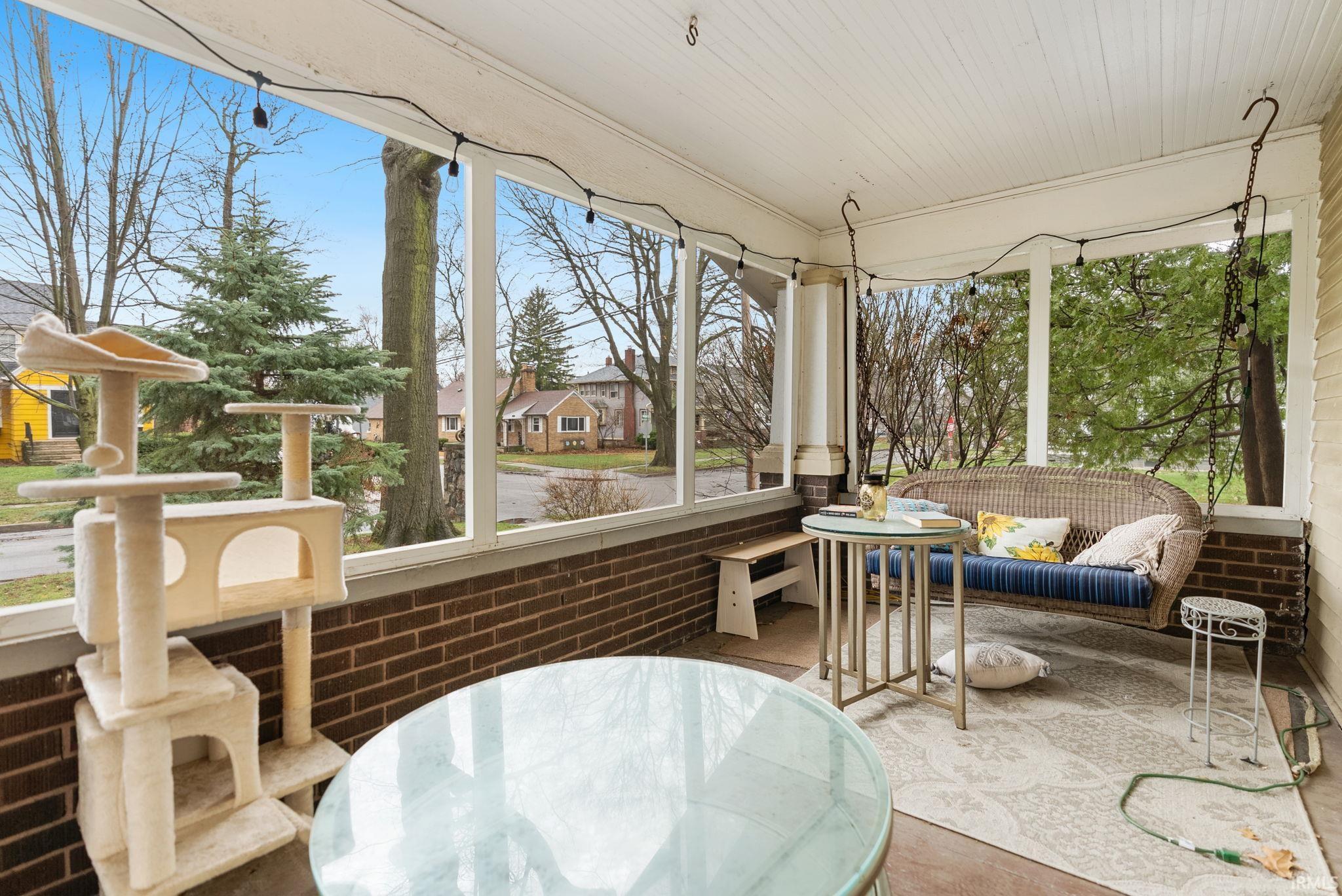Sunroom / solarium featuring brick wall, a residential view, and wooden ceiling